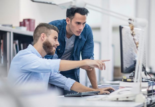 Team of developers working together in the office review information on a computer.