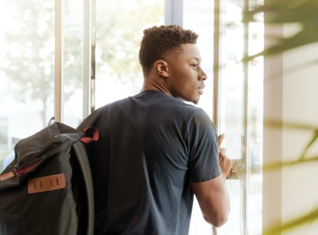 College student pushing open a door and looking back