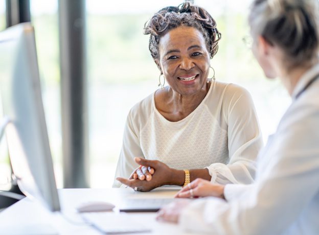 Older female client sitting with medical professional reviewing information on computer screen.